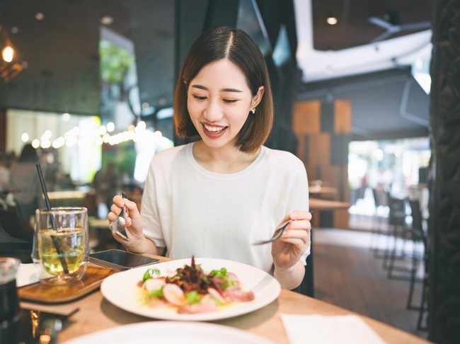 Weekend city break people lifestyle concept. Young adult asian woman eating healthy food diet meal. At indoors cafe restaurant on day. Happy smile face and short hair person.