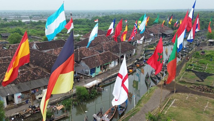 Foto udara sejumlah bendera negara peserta Piala Dunia 2026 berkibar di dermaga Desa Gerongan, Kecamatan Kraton, Kabupaten Pasuruan, Jawa Timur, Jumat (12/6/2026). Warga di desa tersebut mengibarkan bendera negara tim favorit mereka sebagai bentuk du