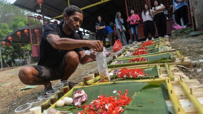 Warga meletakan uang pada sesajen saat tradisi Lepas Ancak di Kota Tangerang, Banten, Jumat (12/6/2026). Tradisi melarung sesajen pada sembilan titik di aliran Sungai Cisadane tersebut sebagai ucapan rasa syukur, permohonan keberkahan dan penghormatan kepada leluhur jelang penyelenggaraan Festival Peh Cun yang jatuh pada Jumat (19/6). ANTARA FOTO/Putra M. Akbar