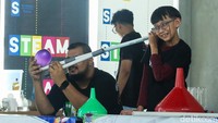 Pemandu memperagakan sejumlah percobaan yang menampilkan fenomena ilmiah secara langsung di hadapan peserta.