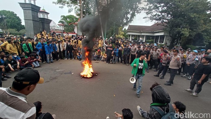 Aliansi mahasiswa Banyumas Raya membakar ban saat menggelar aksi di depan Kantor Bupati Banyumas, Sabtu (13/6/2026).