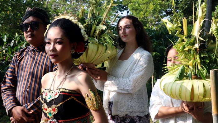 Pemuka adat menuntun sepasang muda mudi pembawa biji kopi lanang (laki-laki) dan wadon (perempuan) yang sudah dikawinkan saat tradisi upacara temanten kopi di perkebunan Kopi De Karanganjar, Blitar, Jawa Timur, Minggu (14/6/2026). Tradisi Temanten Kopi merupakan ritual memilih dan memetik kopi lanang dan wadon terbaik yang kemudian digiling bersamaan sebagai penanda masuknya musim panen dan giling biji kopi yang rutin dilakukan masyarakat perkebunan kopi lereng Gunung Kelud sebagai wujud rasa syukur atas hasil panen yang melimpah serta kualitas biji kopi yang baik. ANTARA FOTO/Irfan Anshori/kye