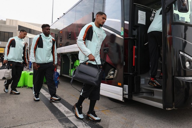 Tiba di bandara Logan International Airport in Boston, Maxence Lacroix dan kawan-kawan kompak dengan training suit mereka. Outfit sporty itu dikontraskan dengan tas hitam Bottega Veneta yang klasik dan elegan. (Foto: Franck FIFE/AFP)