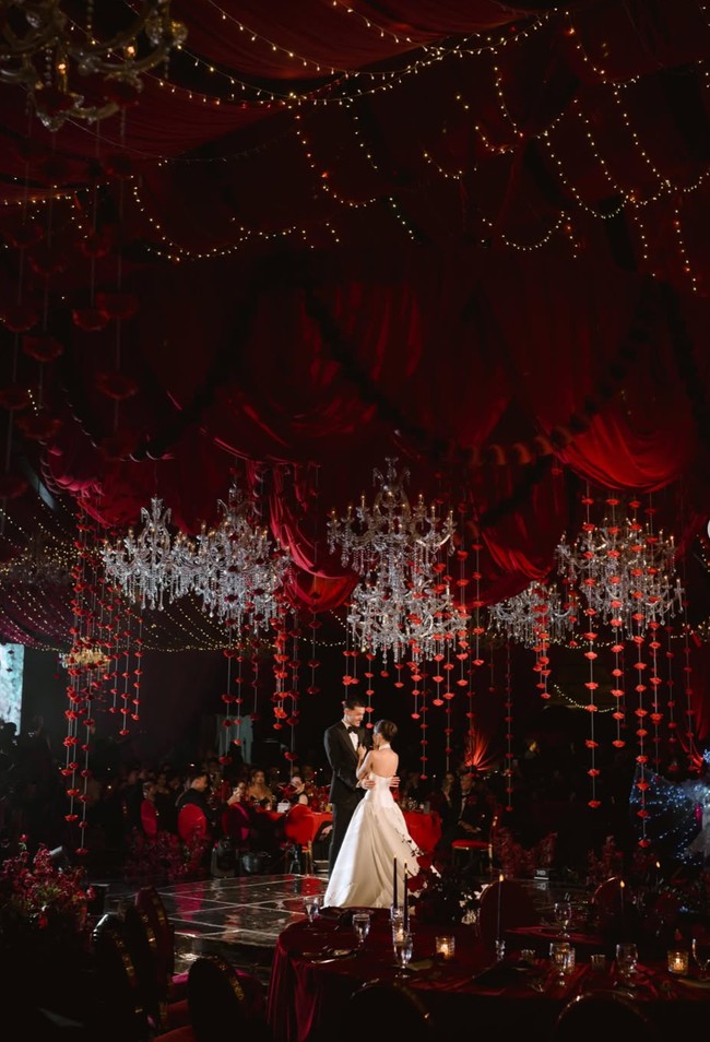 Kali ini dekorasi resepsinyaa berkonsep dramatic red romance. Elemen paling dominan adalah kain merah marun dan merah ruby yang menjuntai memenuhi seluruh plafon. Drapery disusun berlapis-lapis membentuk gelombang dan lipatan dramatis sehingga ruangan terasa seperti tenda kerajaan mewah. Foto: Instagram/@jennifercoppenreal20/@justinhubner5