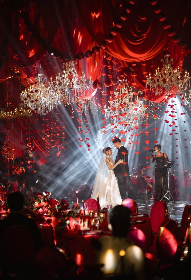 Di antara kain merah menggantung banyak chandelier kristal berukuran besar dengan cahaya warm gold. Instalasi mawar merah menggantung yang menciptakan efek dramatis juga tak kalah bikin terpukau. Foto: Instagram/@jennifercoppenreal20/@justinhubner5