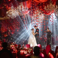 Di antara kain merah menggantung banyak chandelier kristal berukuran besar dengan cahaya warm gold. Instalasi mawar merah menggantung yang menciptakan efek dramatis juga tak kalah bikin terpukau. Foto: Instagram/@jennifercoppenreal20/@justinhubner5