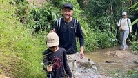 Kali ini Omesh dan Langit menyusuri aliran air dangkal yang berbatu. Omesh yang mengenakan kaos hitam lengan panjang dan celana kargo tampak mengawasi Langit yang berjalan di depannya. Langit terlihat fokus melangkah di atas bebatuan, dibantu oleh tongkat pendakinya. (Foto: dok Instagram omeshomesh)