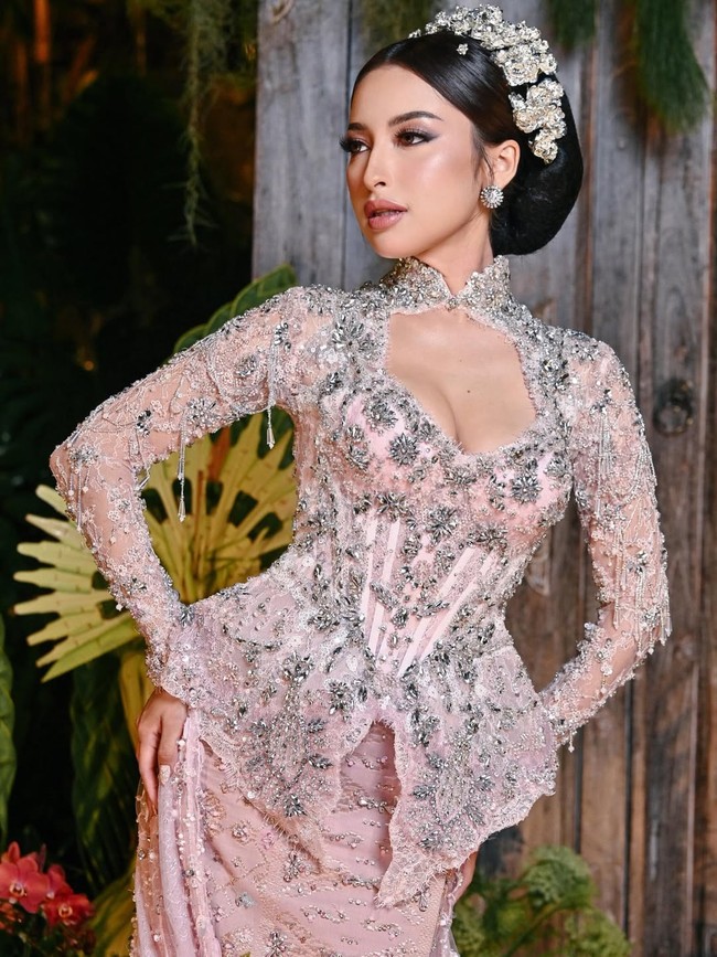 Setelah resmi menikah, sore harinya di tanggal yang sama, Jennifer dan Hubner menggelar acara intimate welcome dinner. Ibu satu anak itu kembali tampil memukau berbalut busana bernuansa pink yang dirancang khusus oleh Maison Baaz Couture. Kebaya modifikasi tersebut memiliki kerah tinggi dengan detail payet yang menghiasi seluruh bagian busana. Pada bagian dadanya terdapat detail cut-out yang memberikan sentuhan modern. Melengkapi penampilannya, rambut Jennifer disanggul rapi dengan hiasan bunga khas Bali berwarna putih yang memperkuat nuansa tradisional. Makeup flawless dengan sentuhan soft glam hasil tangan MUA Kun Soo semakin memancarkan kecantikannya. Foto: Resepsi pernikahan Jennifer Coppen dan Justin Hubner dengan busana adat Bali modifikasi. (Instagram @jennifercoppenreal20)