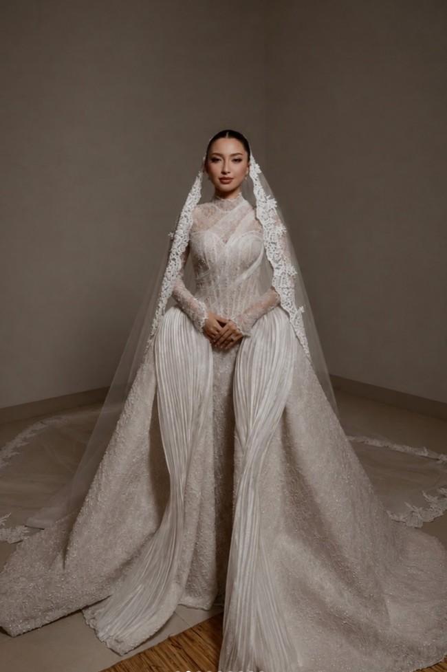 Pada tanggal 14 Juni Jennifer dan Hubner menggelar acara wedding vows. Jennifer tampil santun dengan gaun putih panjang rancangan desainer Christie Basil. Gaun putih berlayer dengan kerah tinggi itu dilengkapi dengan kerudung panjang menerawang. Wajahnya dipulas dengan riasan flawless hasil tangan MUA Leo Afandi. Sementara rambutnya tertata rapi dengan model sanggul sleek yang membuat penampilannya terlihat clean. Foto: Instagram/@bychristiebasil