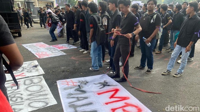 Massa aksi membentangkan spanduk tuntutan di depan Gedung DPRD Kota Malang
