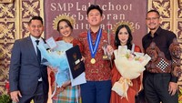 Di depan latar belakang bertuliskan SMP Labschool Kebayoran Kelulusan 2026, Melanie Putria bersama suaminya, Aldico Sapardan, dan Angga Puradiredja, dengan istrinya, Dewi Andarini, berfoto bersama dengan senyum semringah. Sang anak, Sheemar Rahman Puradiredja, berdiri di tengah dengan bangga mengenakan medali kelulusan. (Foto: dok Instagram melanieputria)