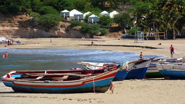 Dari Kejutan Piala Dunia ke Surga Atlantik, Pesona Tanjung Verde Mencuri Perhatian Tarrafal beach Cabo Verde Santiago view of Tarrafal beach with white sand, clear water, coconut palms and colourful boats. Tarrafal is located in the north of the island of Santiago in the Cape Verde archipelago off the coast of Senegal. It was a sunny day in December and a fisherman was walking on the beach