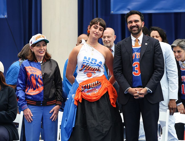 Dalam perayaan kemenangan Knicks setelah 53 tahun, Rama Duwaji memadukannya dengan anting pom pom oranye, tumpukan kalung emas, dan rok midi juga sneakers Nike Air Rift.Foto: Getty Images/Angelina Katsanis