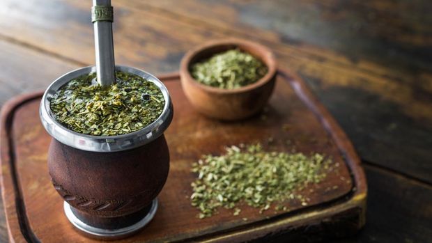 Traditional Argentinian yerba mate tea in a calabash gourd with bombilla stick against wooden background