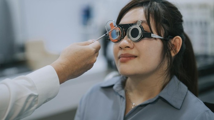 Asian doctor performing eye test with young female patient with disability on Optical vision test vector chart in clinic