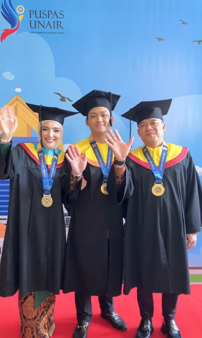 Rona bahagia terpancar jelas dari wajah Ashanty, Azriel, dan Anang Hermansyah saat mereka kompak melambaikan tangan ke arah kamera dalam balutan toga Universitas Airlangga. Foto: Dok. Instagram @ashanty_ash.
