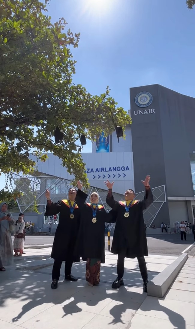 Penuh dengan keceriaan dan ekspresi penuh kelegaan, ketiganya berpose melempar topi wisuda ke udara di halaman depan gedung Universitas Airlangga. Foto: Dok. Instagram @ashanty_ash.