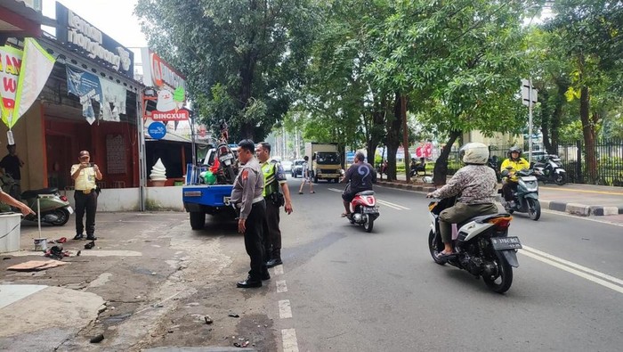 Polisi mengecek TKP mobil BMW listrik yang dirusak massa setelah menabrak motor di Jakarta Barat, Senin (22/6/2026).
