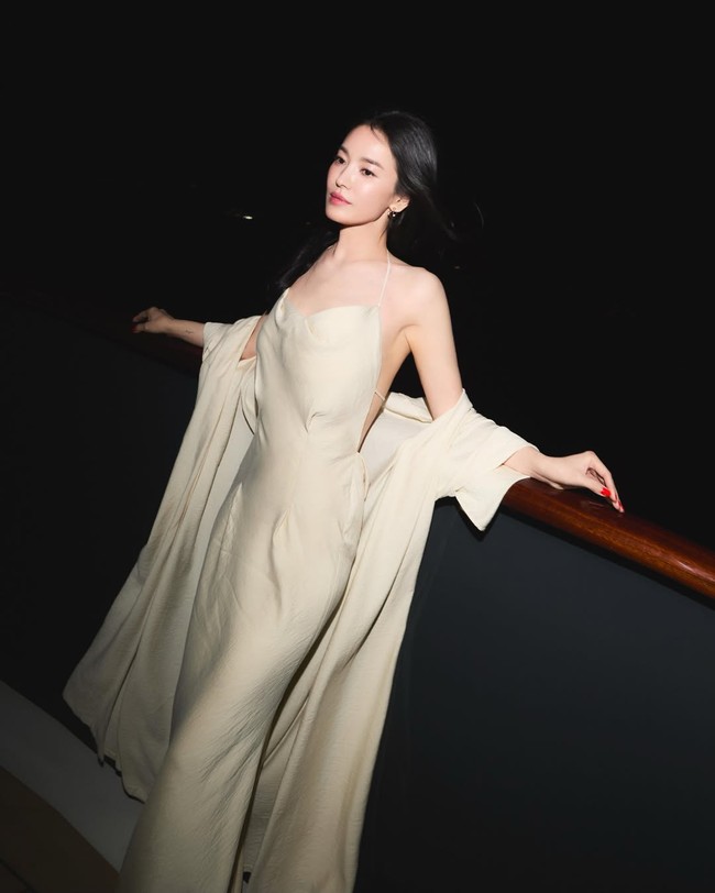 Bintang drama Korea The Glory itu memancarkan keanggunan berpose di atas balkon kapal. Tampil berbalut gaun satin bertali spaghetti keluaran Ses Reves. Foto: dok. Instagram @kyo1122