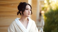 Ini persiapan Aisyah Aqilah saat jadi bridesmaid. Ia terlihat masih memakai jubah mandi tebal berwarna krem dengan rambutnya yang disanggul terdapat tusuk konde hias berwarna emas dan anting. (Foto: dok Instagram aisyahaqilahh)