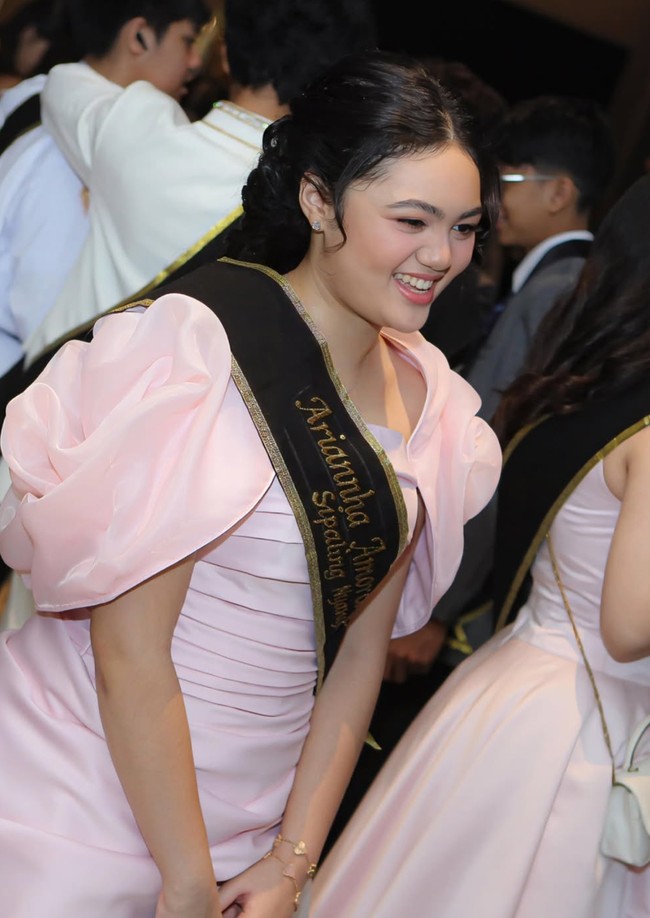 Gaun panjang yang dikenakan Amora memiliki kombinasi warna pink pastel dan putih ivory. Bagian atas gaun didesain strapless dengan detail draping atau lipit-lipit horizontal yang membuat siluet tubuh terlihat lebih rapi. Ada aksen oversized puff sleeves transparan berwarna pink di kedua bahu, membuat look terlihat dramatis. Foto: Instagram/@amora_lemos05