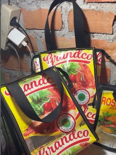 Daur ulang kreatif limbah plastik kemasan minyak goreng menjadi tas jinjing belanja yang unik, estetis dan bernilai guna menggunakan sebuah mesin jahit.