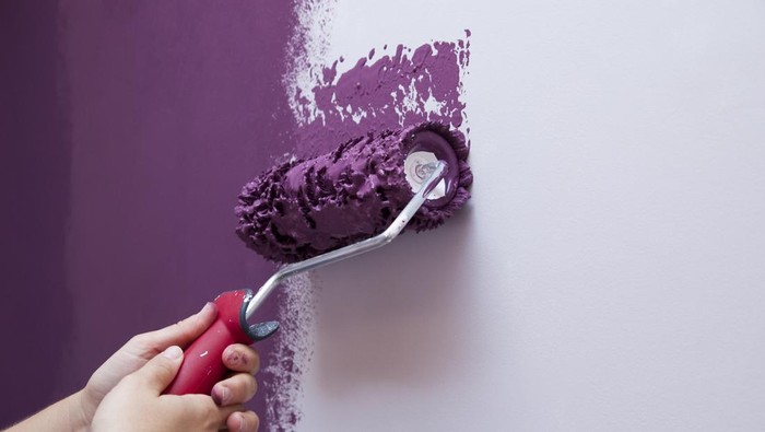 Two hands (woman) pinting the wall with a paint roller