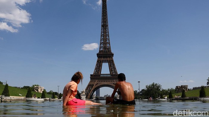 People cool off in the Trocadero Fountain next to the Eiffel Tower in Paris as temperatures rise during a heatwave affecting a large part of France, June 22, 2026. REUTERS/Abdul Saboor