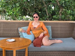 Wulan memadukan atasan oranye menerawang dengan rok cokelat berbelahan tinggi, Wulan tampil memukau. Gayanya makin stylish dengan aksesori berupa kalung emas 2 layer, anting, gelang, dan kaca mata hitam. Foto: Instagram/@wulanguritno