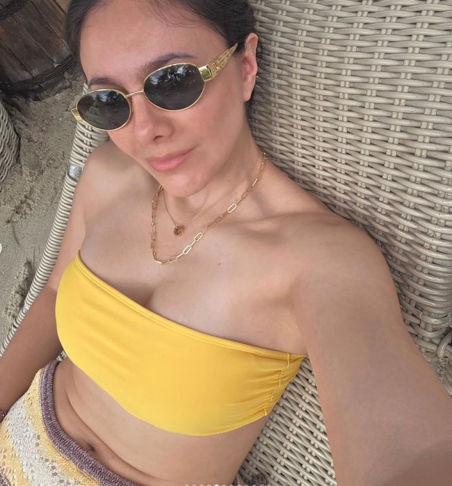 Tampil seksi bergaya bak ABG, Wulan memadukan bikini top model bandeau warna kuning dengan rok rajut. Wajahnya terlihat natural tanpa pulasan makeup. Foto: Instagram/@wulanguritno