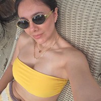 Tampil seksi bergaya bak ABG, Wulan memadukan bikini top model bandeau warna kuning dengan rok rajut. Wajahnya terlihat natural tanpa pulasan makeup. Foto: Instagram/@wulanguritno