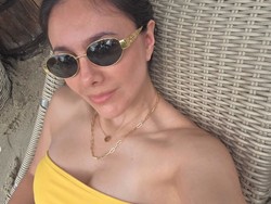 Tampil seksi bergaya bak ABG, Wulan memadukan bikini top model bandeau warna kuning dengan rok rajut. Wajahnya terlihat natural tanpa pulasan makeup. Foto: Instagram/@wulanguritno