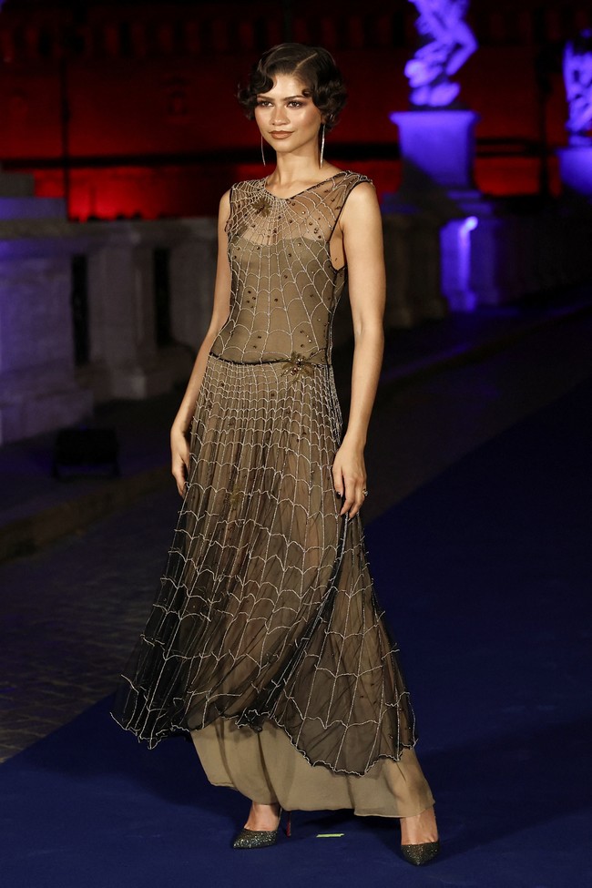 Selama tur promosi, Zendaya lebih sering tampil dalam balutan busana hitam. Hanya saat menghadiri premiere di Roma, Italia, ia mengenakan rok biru-merah yang dipadukan crop top merah, kombinasi warna ikonis kostum Spider-Man. Saat premier, ia tampil dengan gaun vintage Armani Spring-Summer 1990 berhiaskan detail menyerupai jaring laba-laba. (Foto: REUTERS/Francesco Fotia)