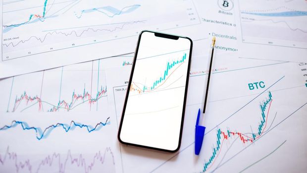bursa-dan-valas-1782350562 Ilustrasi grafik saham dalam latar belakang putih dan layar smartphone