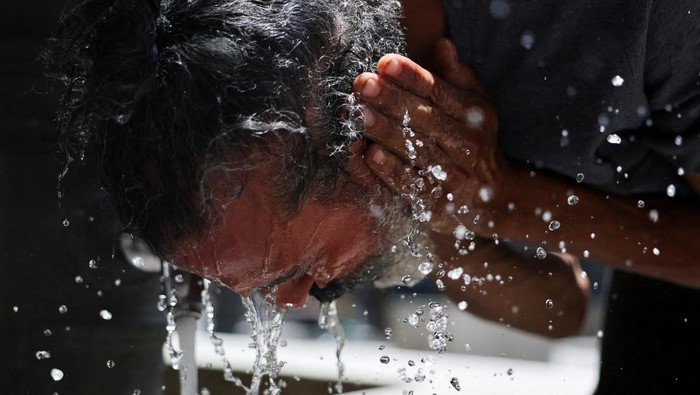 Warga Spanyol mendinginkan diri dengan mencuci muka di tengah gelombang panas yang merajalela (dok. REUTERS/Mohammed Salem)