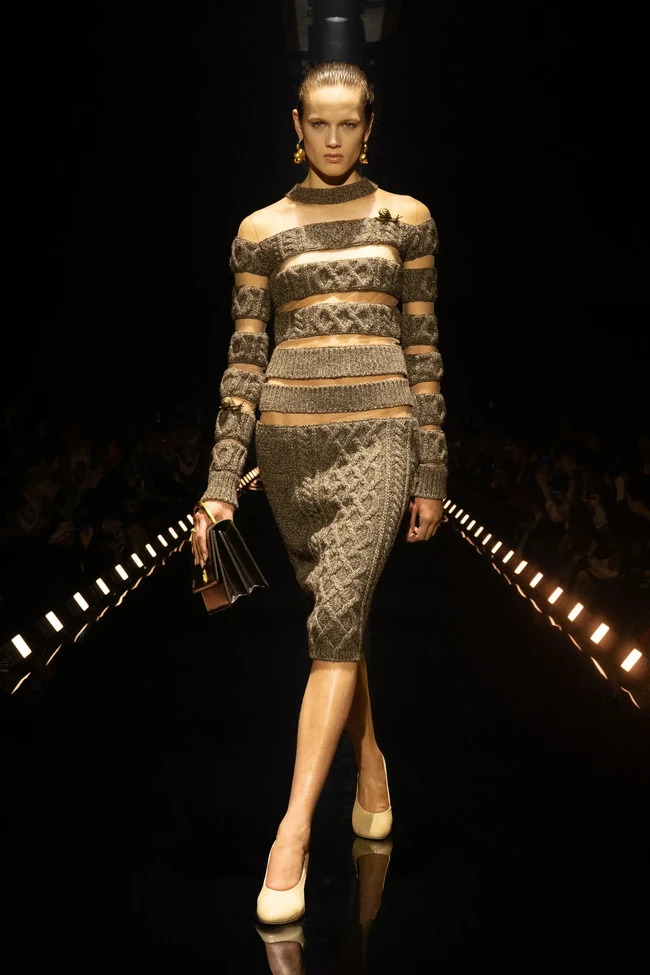 Salah satu eksperimen paling menarik hadir lewat rancangan yang disebut Roseberry sebagai impossible knitwear. Rajutan kabel Aran yang identik dengan kesan tebal dipadukan dengan panel tulle transparan sehingga menciptakan ilusi material berat yang tampak melayang di tubuh. (Foto: Dok. Schiaparelli)