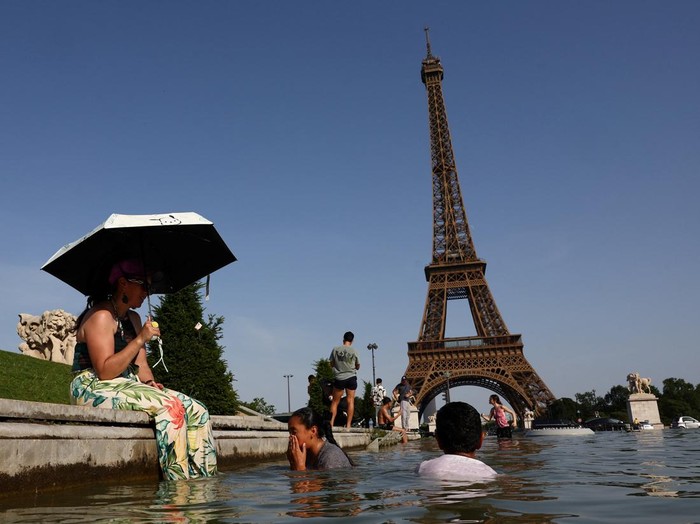 Warga Prancis mendinginkan diri di air mancur di depan Menara Eiffel saat gelombang panas ekstrem melanda (REUTERS/Abdul Saboor)