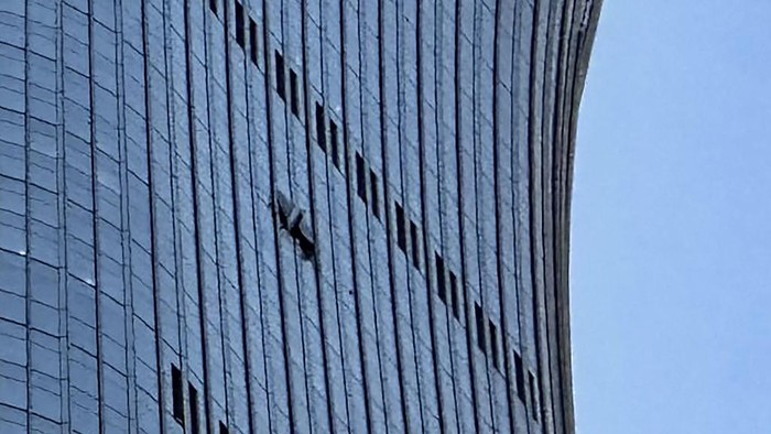 Tampak lubang atau kerusakan pada panel kaca di lantai atas gedung CITIC Tower di Beijing, setelah insiden yang disebut melibatkan pesawat kecil menabrak gedung (AFP/PETER CATTERALL)