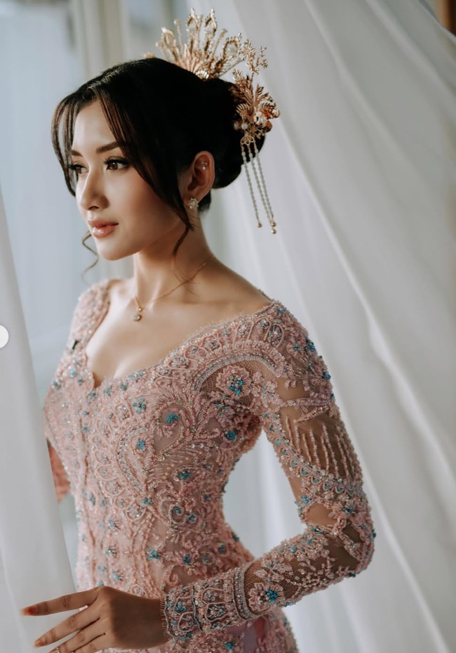 Penampilan Yuriska makin memukau dengan rambut tersanggul yang dilengkapi aksesori emas yang ditusukkan pada sanggulnya. Riasan wajah natural glam hasil tangan MUA Danika Davisca semakin memancarkan pesona cantiknya. Foto: Instagram/@asnawi_bhr