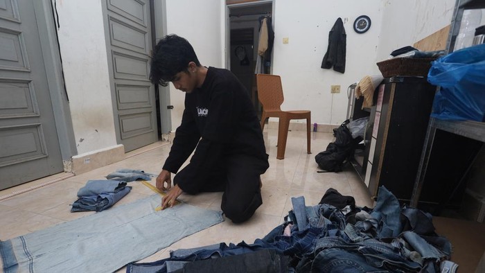 Perajin membuat pola di atas limbah kain jeans di rumah produksi Bumoe, Banda Aceh, Aceh, Sabtu (27/6/2026). Rumah produksi tersebut memanfaatkan limbah kain jeans menjadi berbagai produk, seperti tas, baju, dompet dan sepatu dengan harga berkisar Rp25 ribu hingga Rp500 ribu per produk serta mampu memproduksi hingga 100 produk per bulan sebagai upaya mengurangi limbah tekstil sekaligus meningkatkan nilai ekonomi produk daur ulang. ANTARA FOTO/Akramul Muslim/wsj.