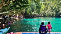 Suasana Labuan Cermin. Terlihat wisatawan menikmati wisata air Labuan Cermin bersama keluarga.