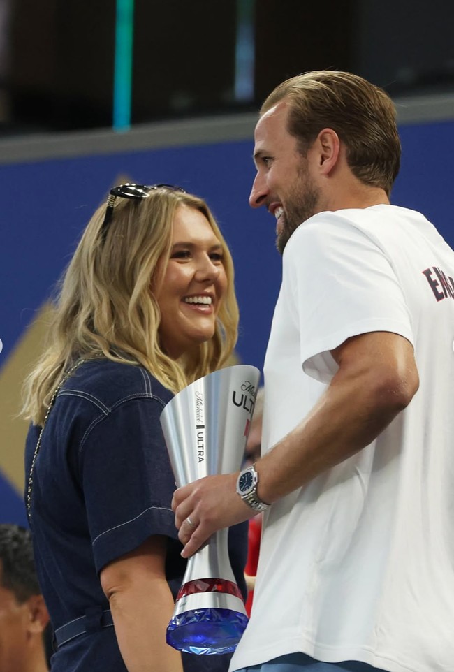 Pesepak bola asal Inggris, Harry Kane, turut mendapat dukungan langsung dari kekasihnya, Katie Goodland. Alih-alih mengenakan jersey, Katie memilih dress jeans. Rambut pirangnya dibiarkan terurai dengan model wavy. Foto: Instagram/@harrykane