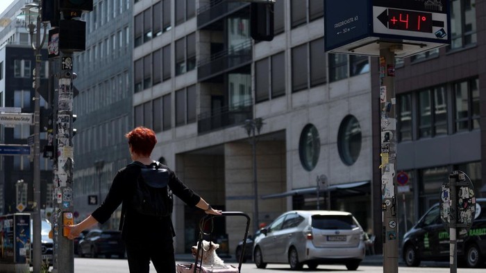 A person pushes her dog in a trolley as a display shows a temperature of 41 degrees Celsius during the ongoing heatwave in the Berlin Mitte district, Germany, June 28, 2026.    REUTERS/Maryam Majd