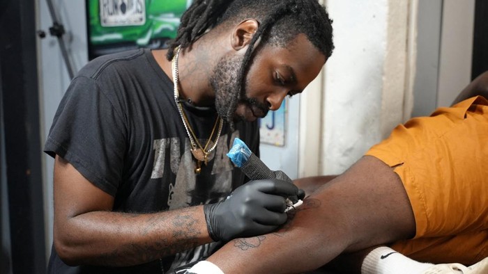 Lyric TheArtist tattoos a FIFA World Cup trophy on a person's leg, in Atlanta, Georgia, U.S. June 25, 2026. REUTERS/Jayla Whitfield-Anderson