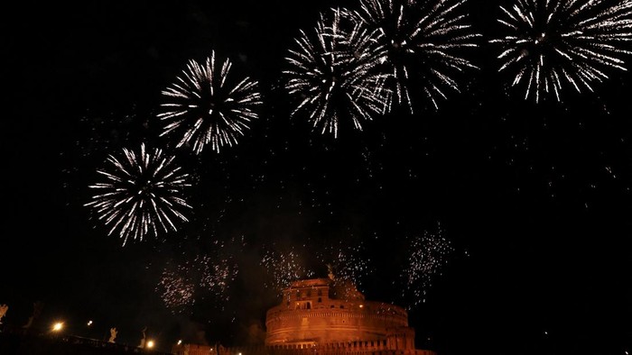 Fireworks light up the sky behind an angel statue on Ponte Sant'Angelo, during the traditional 