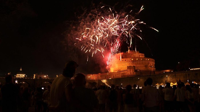 Fireworks light up the sky behind an angel statue on Ponte Sant'Angelo, during the traditional 
