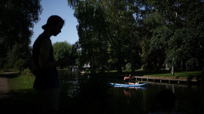 People use umbrellas to shield themselves from the sun while punting on the River Cam as Britain experiences record temperatures during a heatwave disrupting schools and transport networks, in Cambridge, Britain, June 26, 2026. REUTERS/Guglielmo Mangiapane      TPX IMAGES OF THE DAY
