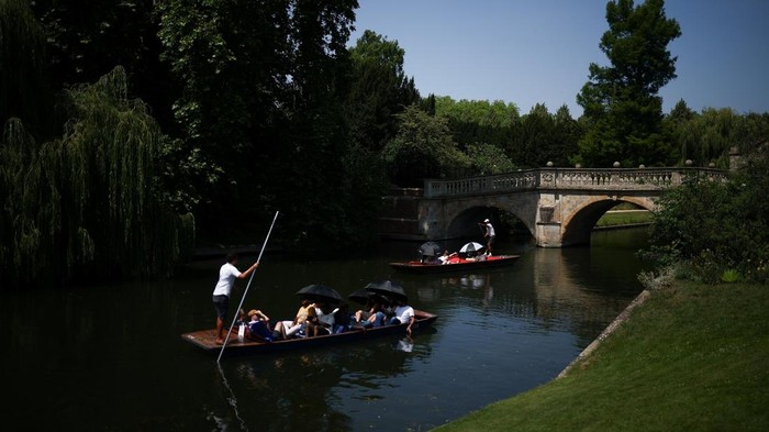 People use umbrellas to shield themselves from the sun while punting on the River Cam as Britain experiences record temperatures during a heatwave disrupting schools and transport networks, in Cambridge, Britain, June 26, 2026. REUTERS/Guglielmo Mangiapane      TPX IMAGES OF THE DAY