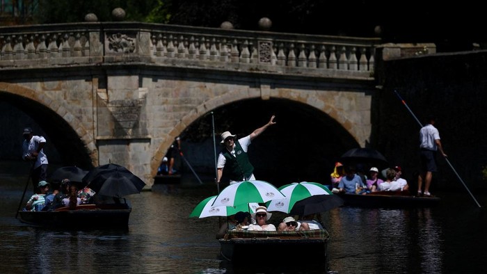 People use umbrellas to shield themselves from the sun while punting on the River Cam as Britain experiences record temperatures during a heatwave disrupting schools and transport networks, in Cambridge, Britain, June 26, 2026. REUTERS/Guglielmo Mangiapane      TPX IMAGES OF THE DAY