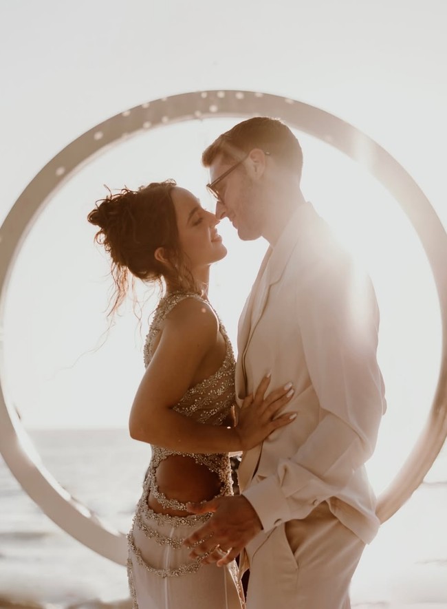 Santiago Gimenez dan Fernanda Serrano menikah dalam sebuah upacara di tepi pantai pada Mei 2024. Pada hari pernikahan tersebut, Fernanda tampil anti main stream bukan memakai gaun pengantin indah. Busana pengantinnya adalah kemben crop top dan rok putih.  Foto: Dok. Instagram ferserranoc